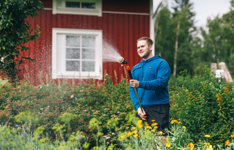 Mies kastelee puutarhaa.
