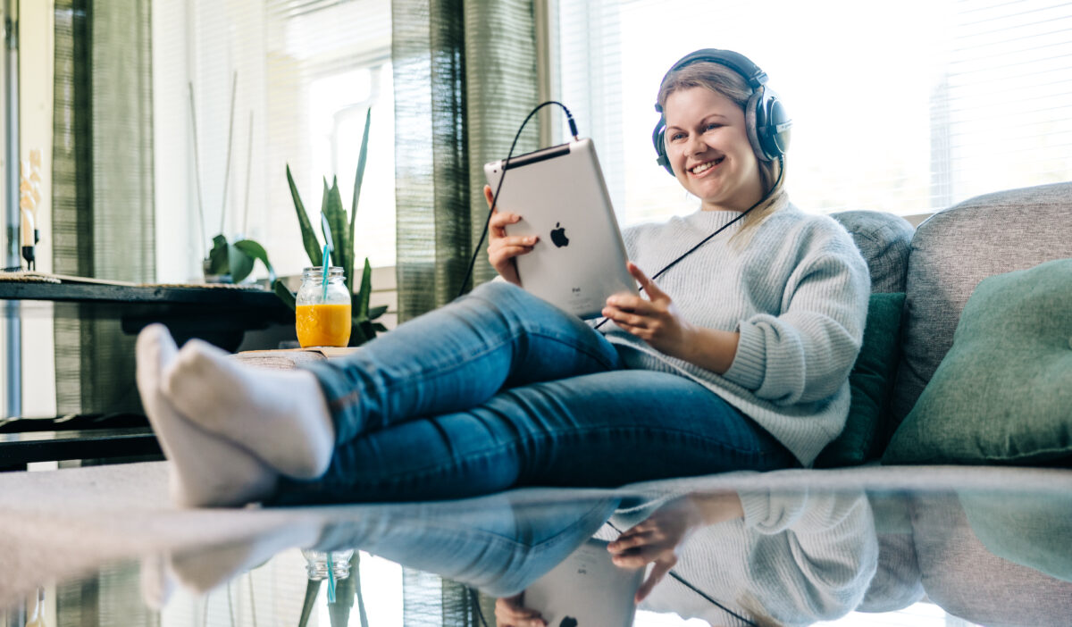 Henkilö istuu sohvalla ja katsoo tablettia