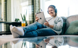 Henkilö istuu sohvalla ja katsoo tablettia