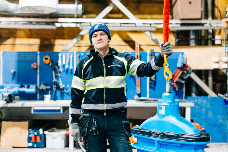 Verkostoasentaja Janne Pitkäjärvi työympäristössään hallissa, työvaatteet päällään.