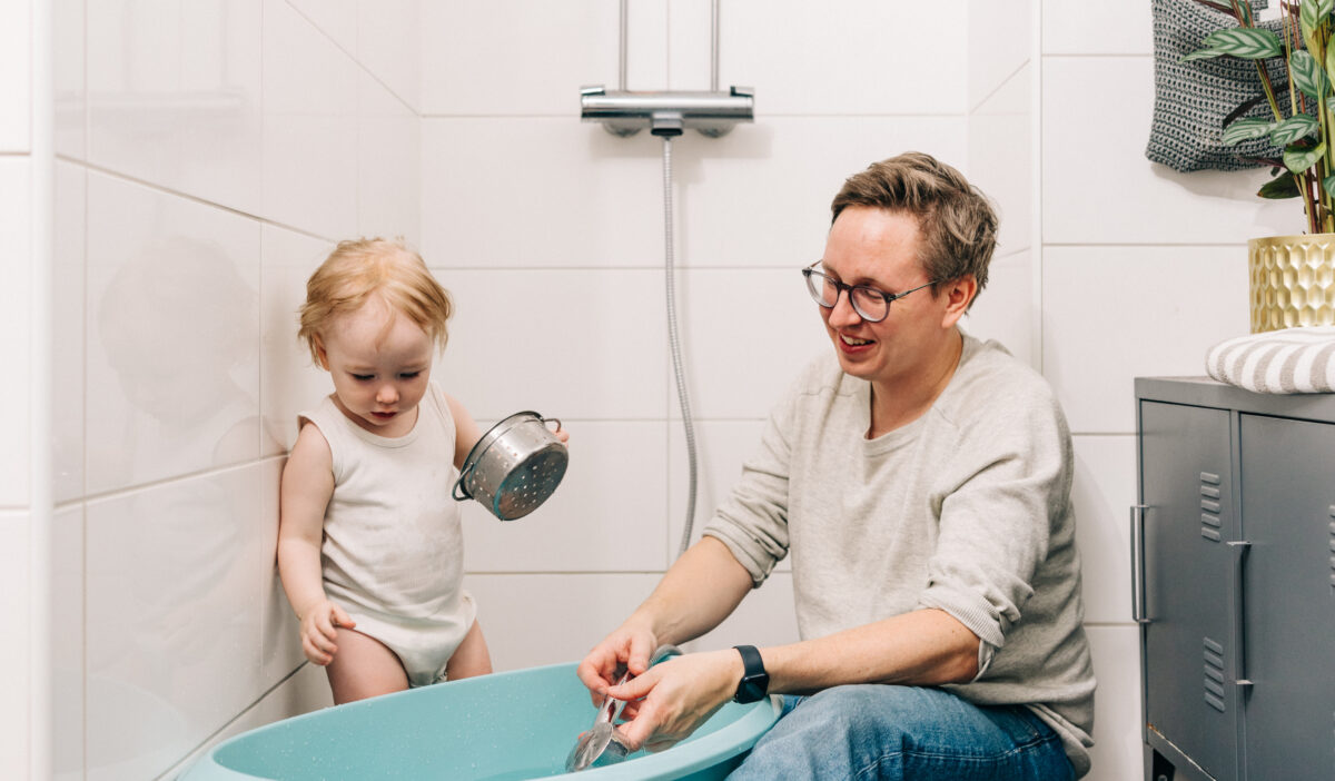 Isä ja lapsi laskemassa kylpyvettä kylpyhuoneessa