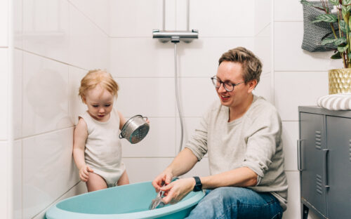 Isä ja lapsi laskemassa kylpyvettä kylpyhuoneessa