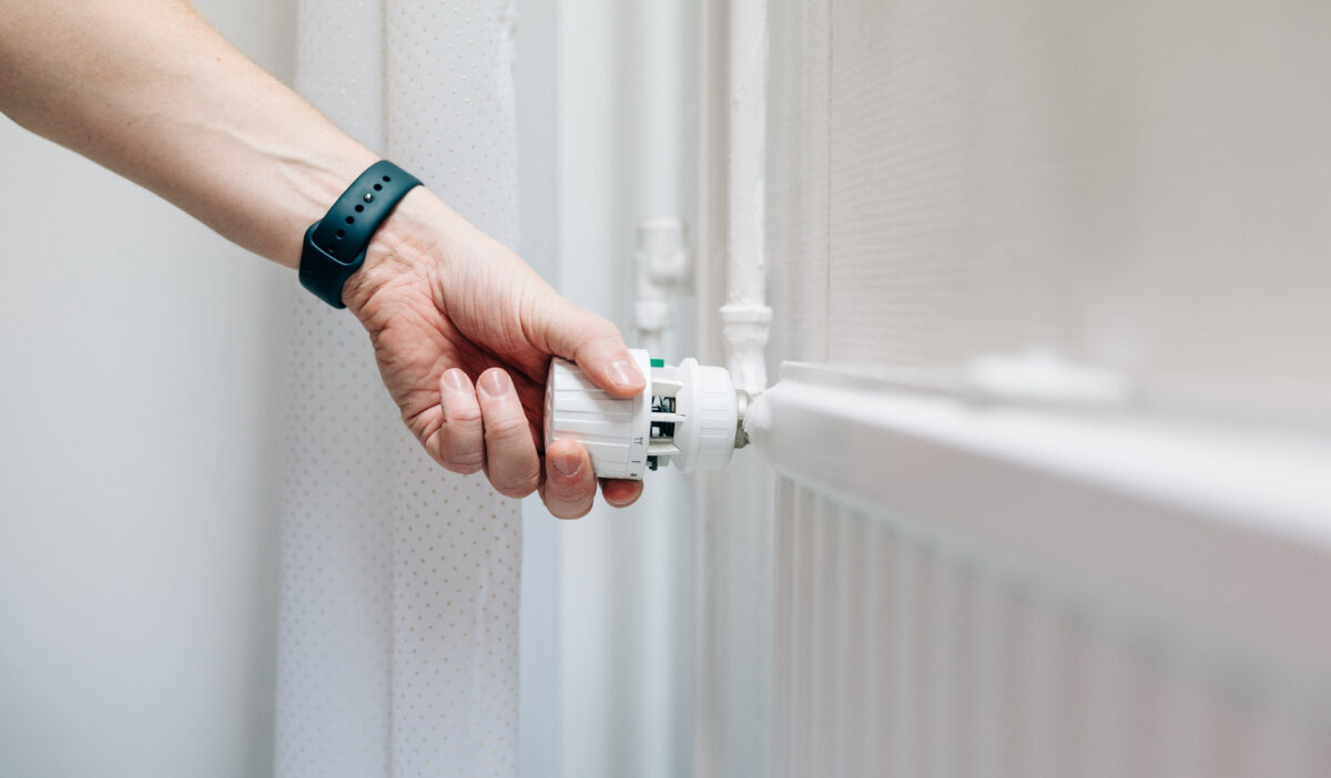 Henkilö säätämässä patterin termostaattia