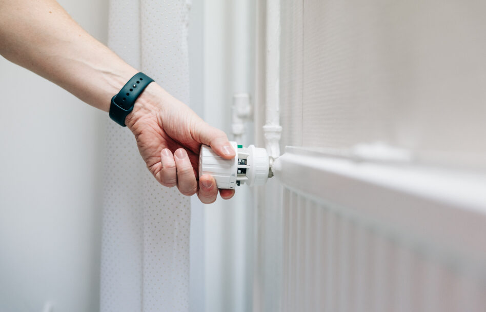 Henkilö säätämässä patterin termostaattia