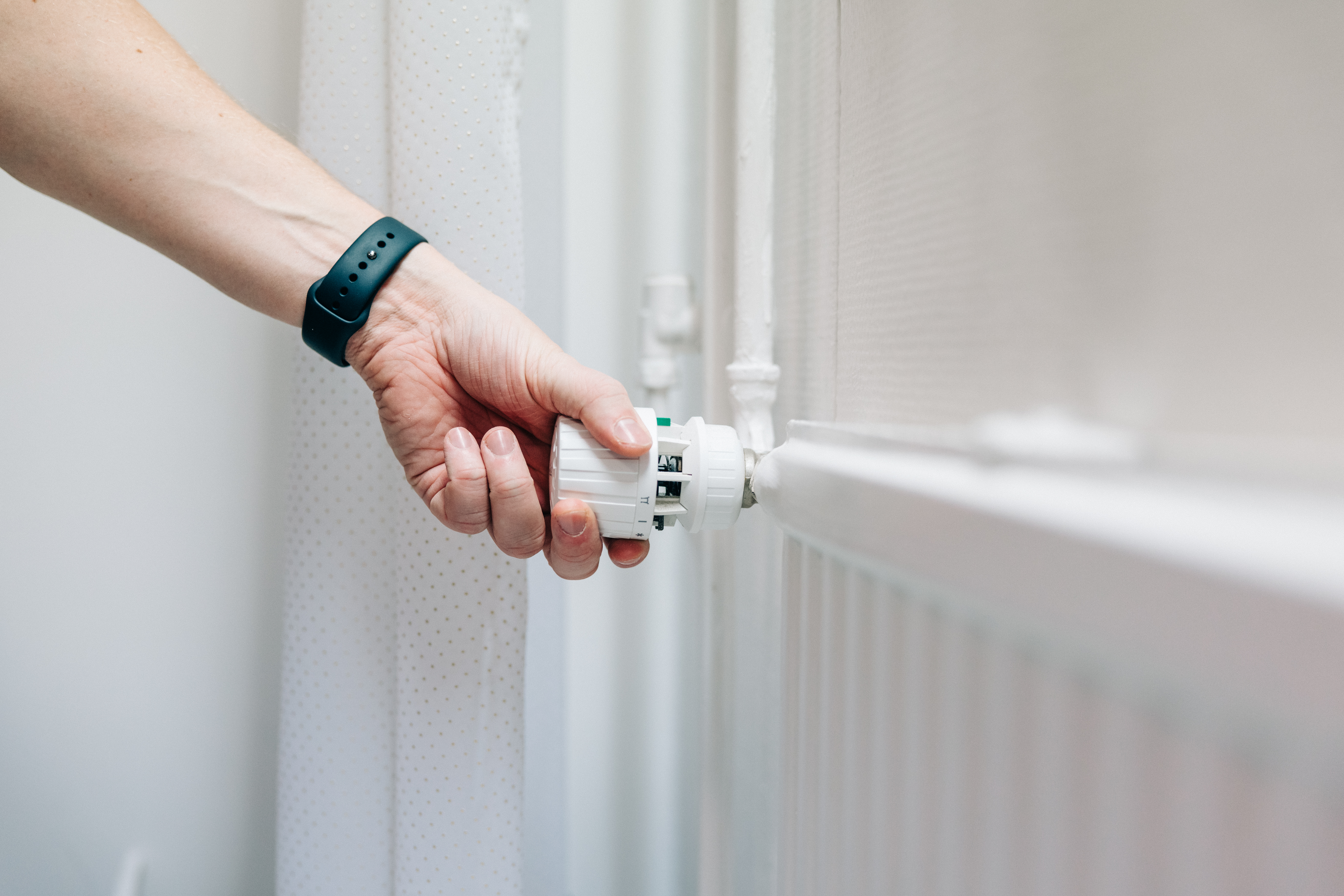 Henkilö säätämässä patterin termostaattia