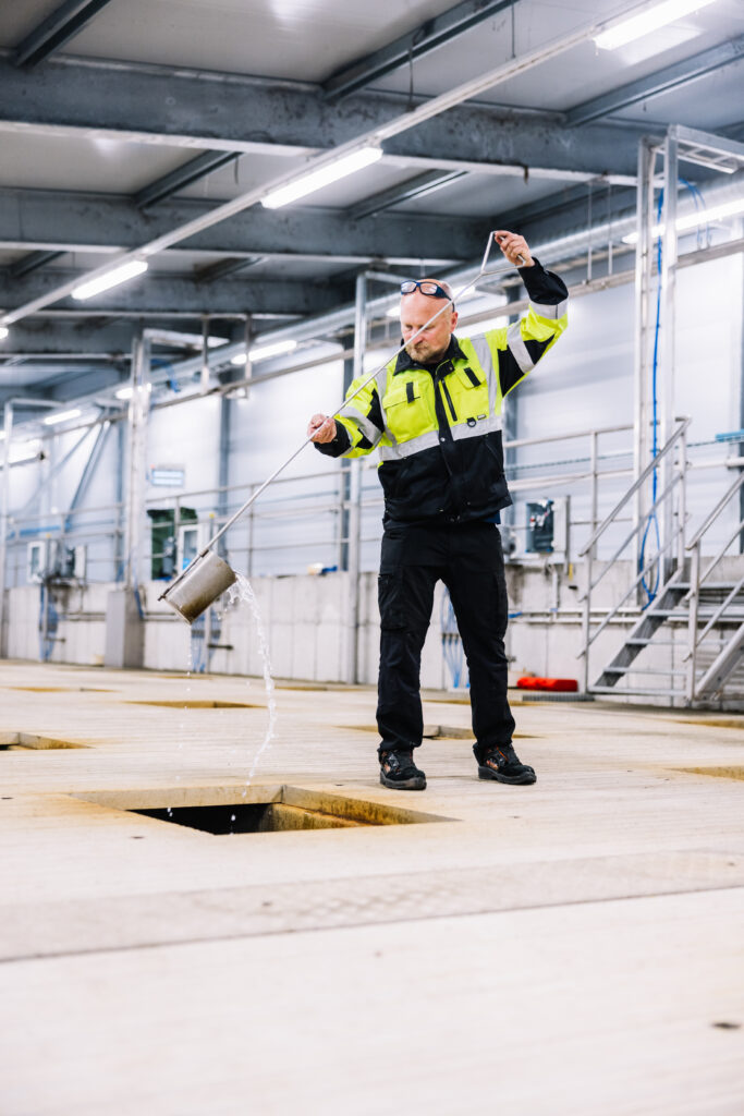 Työntekijä jätevedenpuhdistamolla tutkimassa puhdistettua vettä