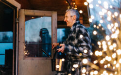 Mies menossa ulkosaunaan jouluvalojen valaistessa.