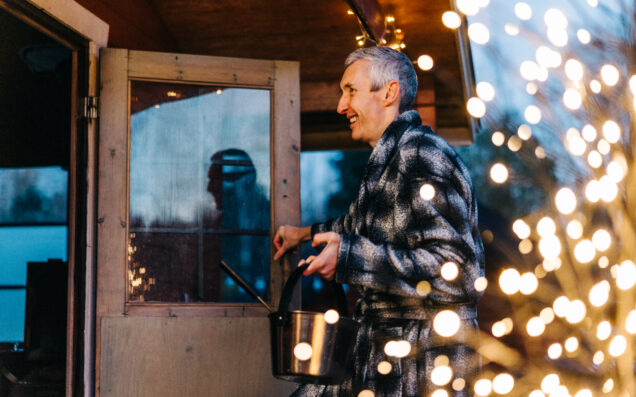 Mies menossa ulkosaunaan jouluvalojen valaistessa.