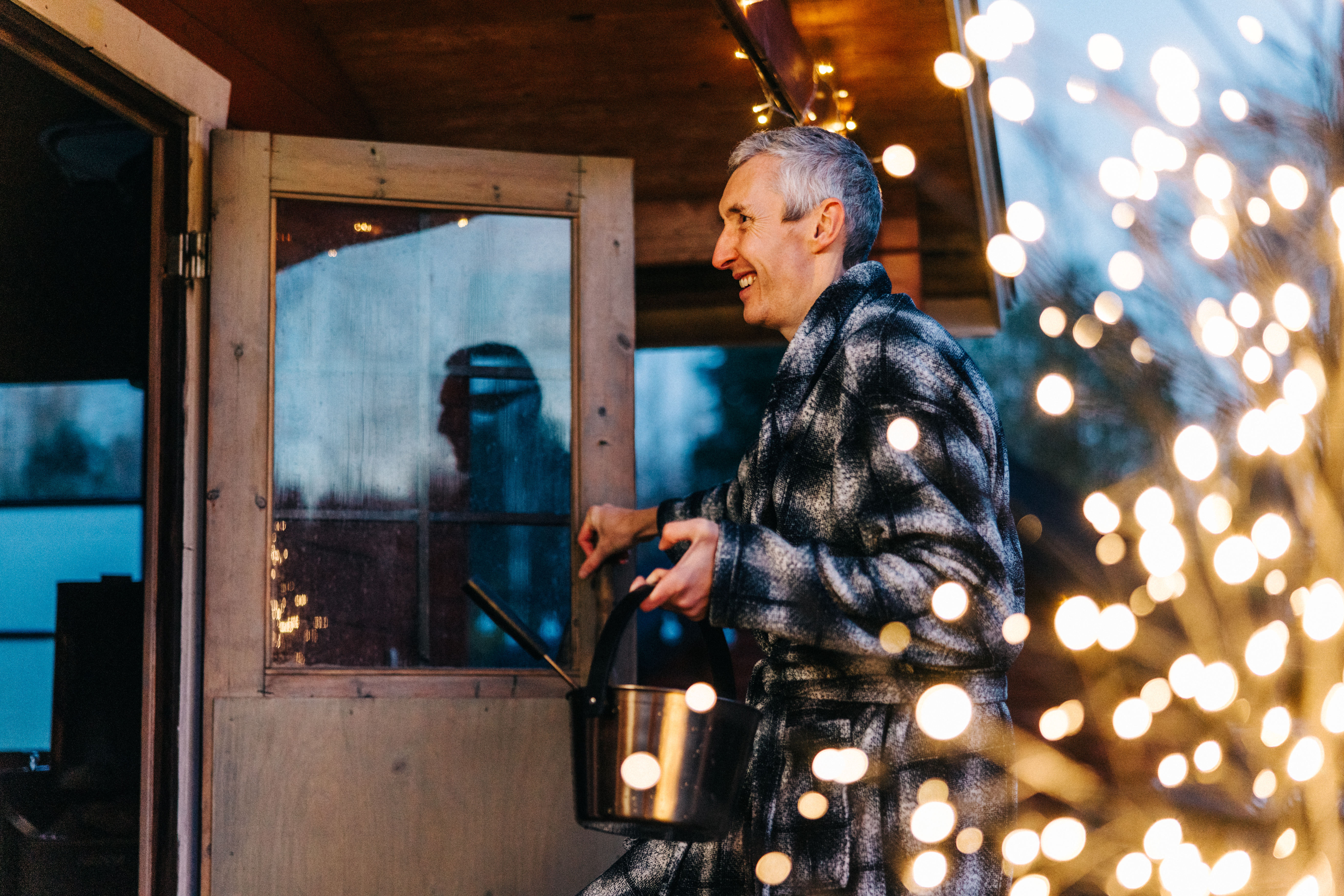 Mies menossa ulkosaunaan jouluvalojen valaistessa.